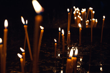 Soft bokeh lights surround the burning candle, creating a spiritual atmosphere
