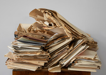 Old, chaotically folded papers, drawings, price lists on a light background, like waste paper.