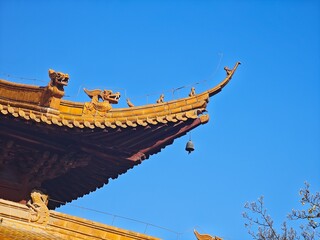 a bell hang on the corner of the roof on an ancient architect under blue sky in sunny day