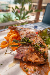 Close up shot of grilled pork chop with curry fried onion and pepper sauce on plate
