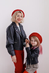 Mom and daughter put on red berets and went on a trip and the girl is sitting on a suitcase
