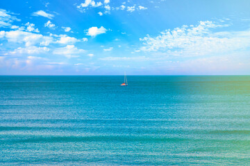 Obraz premium A small yacht with a lowered sail. A lonely boat in the middle of the sea.
