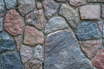 Background with close-up of a wall made of uneven granite blocks of different colors.