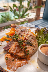 Close up shot of grilled pork chop with curry fried onion and pepper sauce on plate