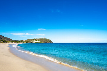 beautiful beach with a blue ocean and a mountain in the background