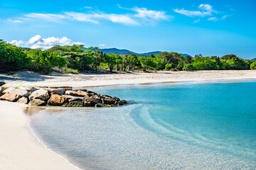 beautiful beach with a blue ocean and a mountain in the background