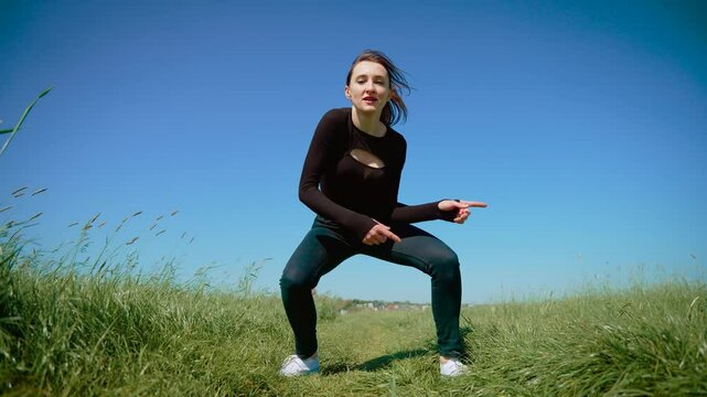 Woman performing stylish contemporary dance in open field, showcasing smooth and confident moves. Female executing modern choreography with energy and flair, embracing current trends. Lady dancing