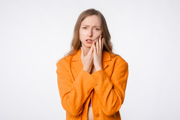 young woman experiencing toothache, standing against a white background. Concept of dental issues and health concerns