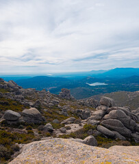Mountain landscape from the summit of La Maliciosa with impressive rock formations, wild vegetation, and a partly cloudy sky. Panoramic view of the Navacerrada Reservoir, perfect for hiking.