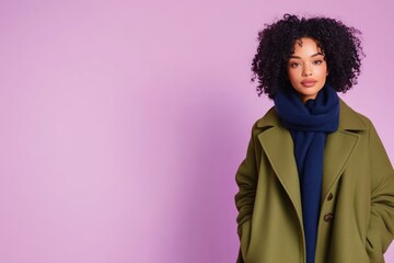 Model in green coat with blue scarf on pink wall