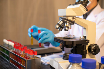 Human hand in glove holding glass jar in modern laboratory. Close-up and long exposure photography.