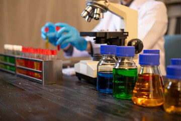 Human hand in glove holding glass jar in modern laboratory. Close-up and long exposure photography.
