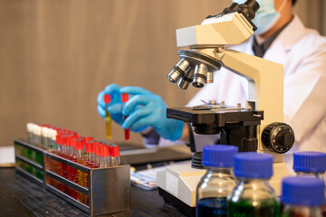 Human hand in glove holding glass jar in modern laboratory. Close-up and long exposure photography.