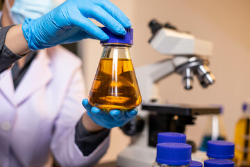 Human hand in glove holding glass jar in modern laboratory. Close-up and long exposure photography.