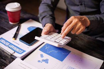 Accountants working on financial investments on calculators, calculating, analyzing business and marketing growth on graphs of various financial documents.
