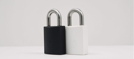 Fototapeta premium Two contrasting padlocks black white against a minimalist white backdrop representing safety and defense