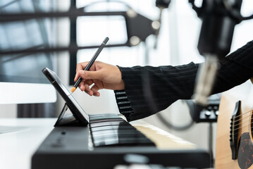 Professional Women Musician composing a song with acoustic guitar, piano keyboard and condenser...