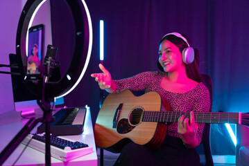 Social media sharing concept. Asian woman musician live streaming online guitar class with...