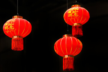 Obraz premium Red Chinese lanterns with gold accents sway gently, symbolizing joy and prosperity during a festive celebration of Chinese New Year in an indoor setting. Bright red lanterns, Lunar New Year.