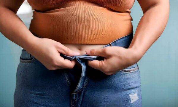 Concept: weight loss, diet, fight against excess weight. A fat girl stands in small pants.