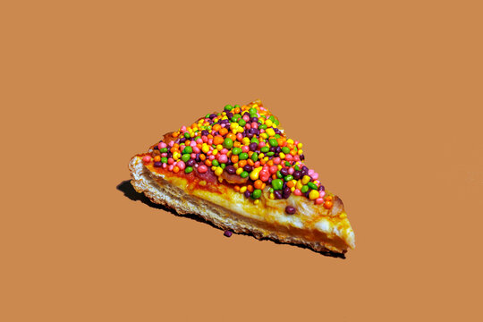 Still life of a sweet candy pizza slice on a brown background