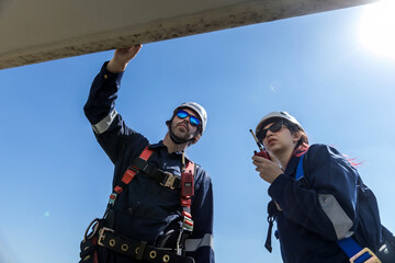 Inspection engineers a rotor blade of a wind turbine. Professional Man Maintenance engineers working in wind turbine farm. Engineer Man standing among Wind Energy Turbine.