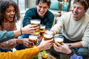 Multi cultural friends cheering, drinking beer glasses at brewery bar restaurant - Group of young people enjoying happy hour sitting at pub table - Food and diverse beverage life style concept