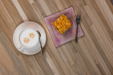 A cup of cappuccino and apple pie on a plate. Dessert on a wooden table.