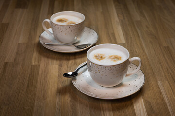 Two cups of cappuccino on a wooden table. Ready to drink.