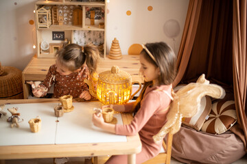 two little girls play in a modern children's room at the table. modern toys and games.
