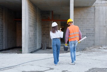 Construction workers inspecting building site progress, teamwork and expertise in construction...