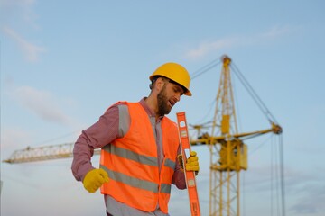 Construction worker wearing safety vest and holding spirit level at construction site