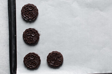 Overhead view of stamped chocolate cookies on a parchment lined baking tray, top view of embossed chocolate sugar cookies on a white background