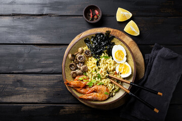  Asian ramen with shrimp, mushrooms, egg and greens on dark wooden background top view copy space for text