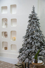 Christmas interior with an elegant Christmas tree decorated with snowy decor and warm garlands. In the foreground are festive gifts in stylish packaging, a decorative gnome and decorations that add co