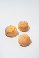 three Brazilian cheese buns on the white background, minimalism with hard shadows