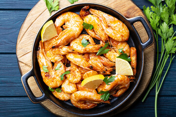  Fried shrimps with lemon and green on a round board, top view, copy space for text