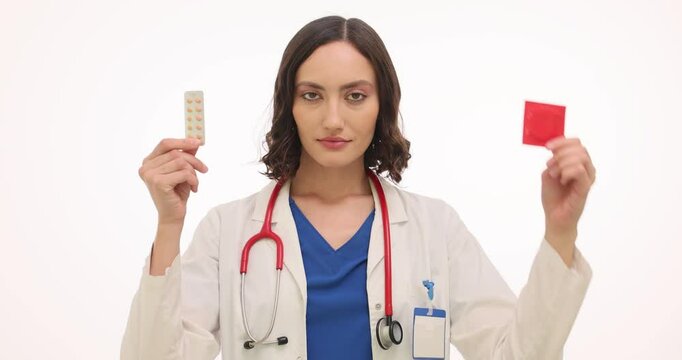 Woman doctor recommends blister of pills and condom on white background. Female gynecologist warns patients about contraception options