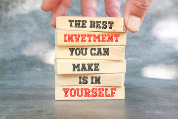 The best investment you can make is to invest in yourself. Motivation quote. Positive affirmation. written on wooden blocks with dark background.