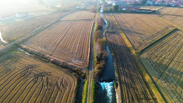 Ripresa aerea di un canale panoramico e paesino in lontananza in 4K, Italia, Risaie, la mora, Ripresa al tramonto per una luce calda e suggestiva, ideale per progetti turistici