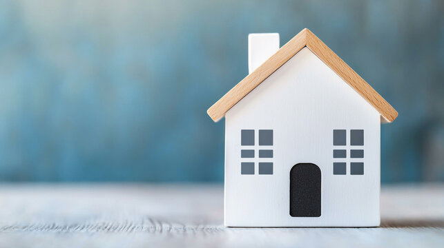Minimalistic model of a house with a wooden roof on a blue background, symbolizing home, real estate, or construction concepts.