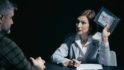 Drug control detective presents an evidence bag to a male suspect during a crime investigation