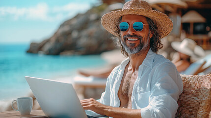 Fototapeta premium Professional using a laptop while sitting at a table by the beach with waves in the background. The concept of work-life balance, working remotely from anywhere in the world.