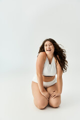 Fototapeta premium Confident plus size woman shines in stylish underwear in a bright space.