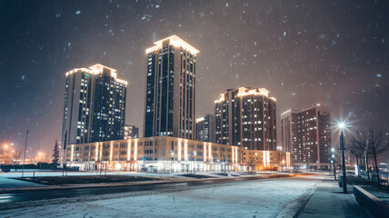 Nighttime snowfall reveals illuminated buildings in a modern urban landscape during winter