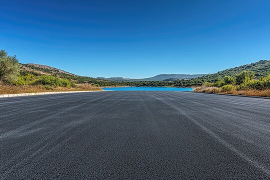 A serene landscape featuring an empty road winding its way through a scenic lake backdrop