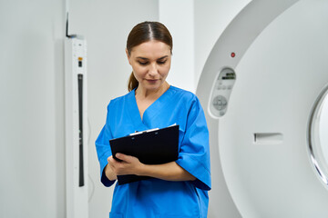 Attractive female doctor in scrubs meticulously reviews patient diagnostics in a radiology area.