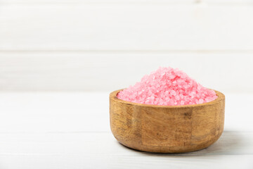 Sea salt for bath with aroma and rose flowers on textured wooden background. Pink sea salt. Spa treatments. Natural salt with herbs and essential oils. skincare concept. Meso for text. Copy space