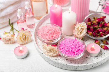 Sea salt for bath with aroma and rose flowers on textured wooden background. Pink sea salt. Spa treatments. Natural salt with herbs and essential oils. skincare concept. Meso for text. Copy space