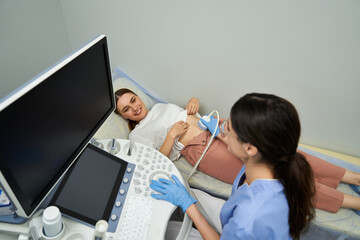 Fototapeta premium A gynecologist performs a detailed ultrasound on a relaxed woman at a modern clinic.